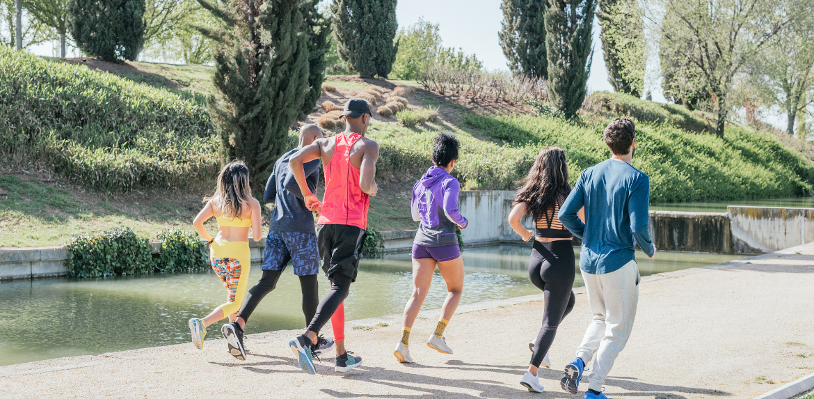 Group of runners training in a park. Rear view, back to camera. Happy and smiling.