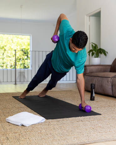 Man Exercising With Dumbbells On Mat At Home