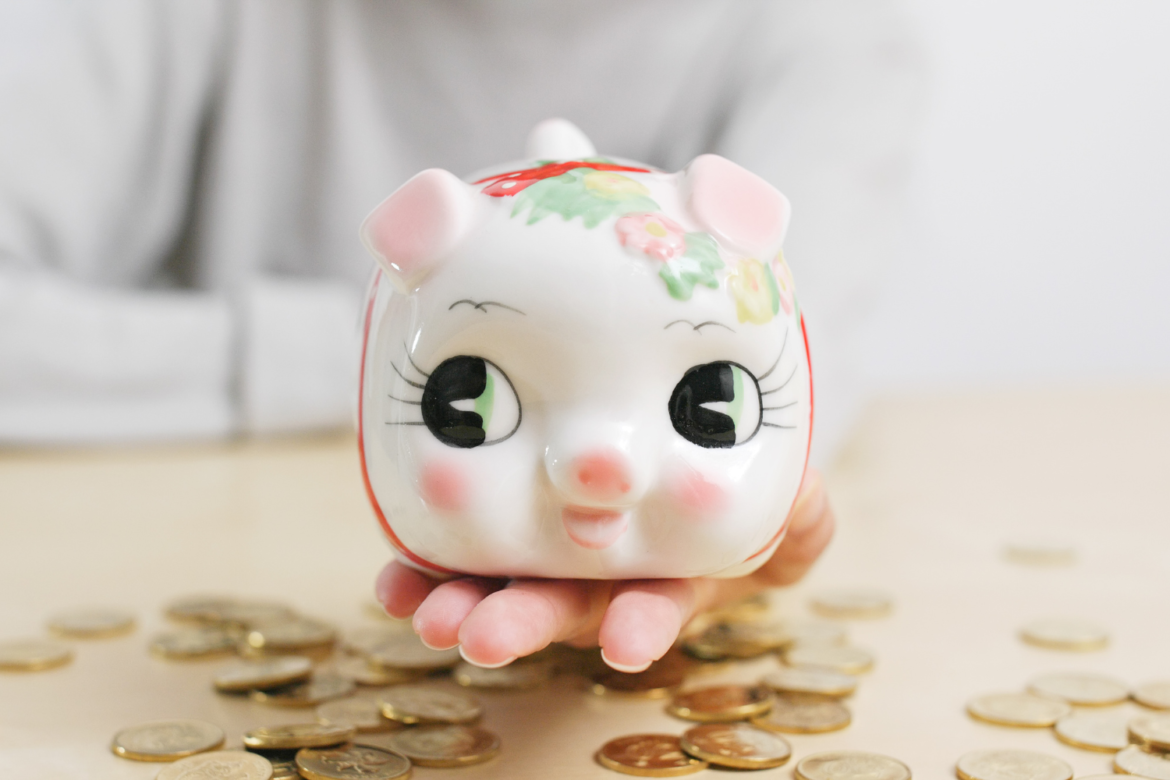 Woman holding piggy bank with coin on the desk